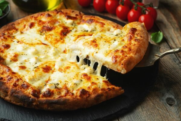 A slice of hot Italian pizza with stretching cheese. Pizza four cheeses with basil.