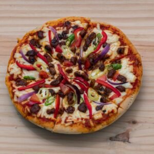 Delicious Devilled Chicken Pizza on a wooden surface overhead top view close-up photograph.