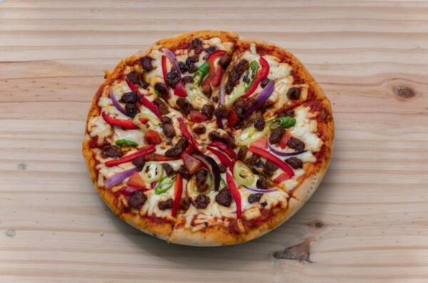 Delicious Devilled Chicken Pizza on a wooden surface overhead top view close-up photograph.