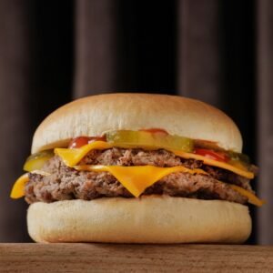 perfect tasty double cheeseburger on wooden table on brown background, bottom view